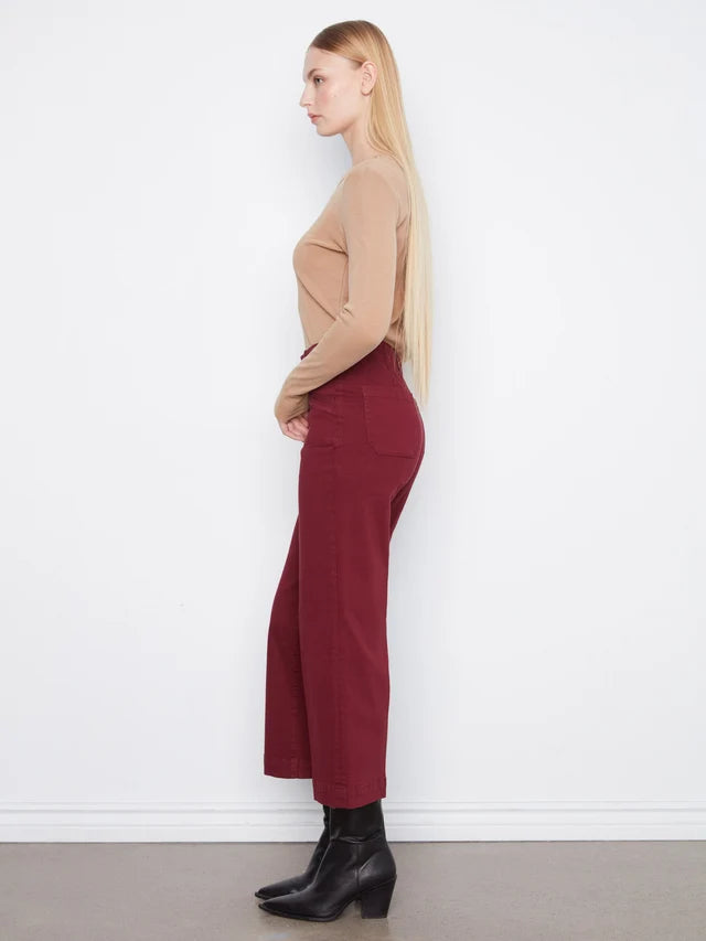 Woman wearing a beige sweater and burgundy pants against a white background