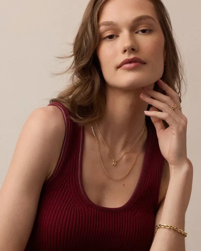 Woman wearing gold necklaces and a bracelet against a neutral background