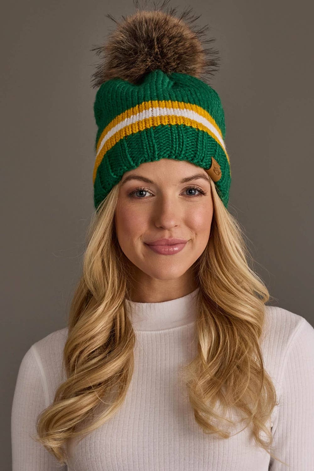 Panache Apparel Co. green, gold, and white striped knit pom hat with faux fur pom