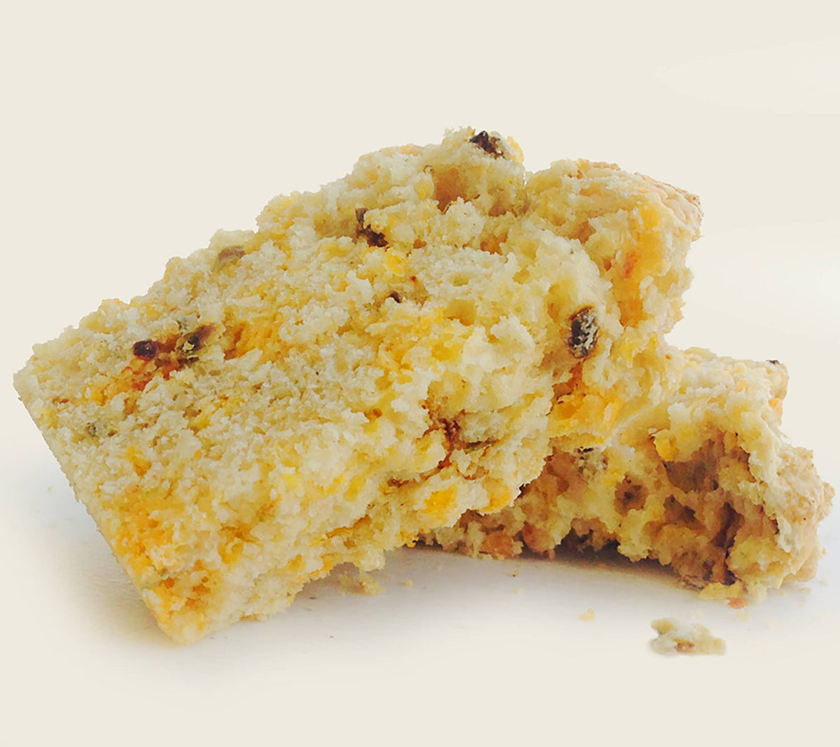 Two pieces of crumbly dessert with raisins on a light background