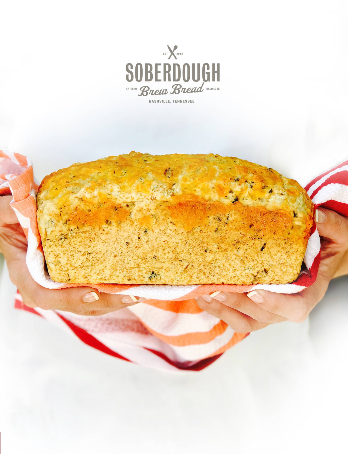 Loaf of bread held by hands with a 'Soberdough Brew Bread' label above.