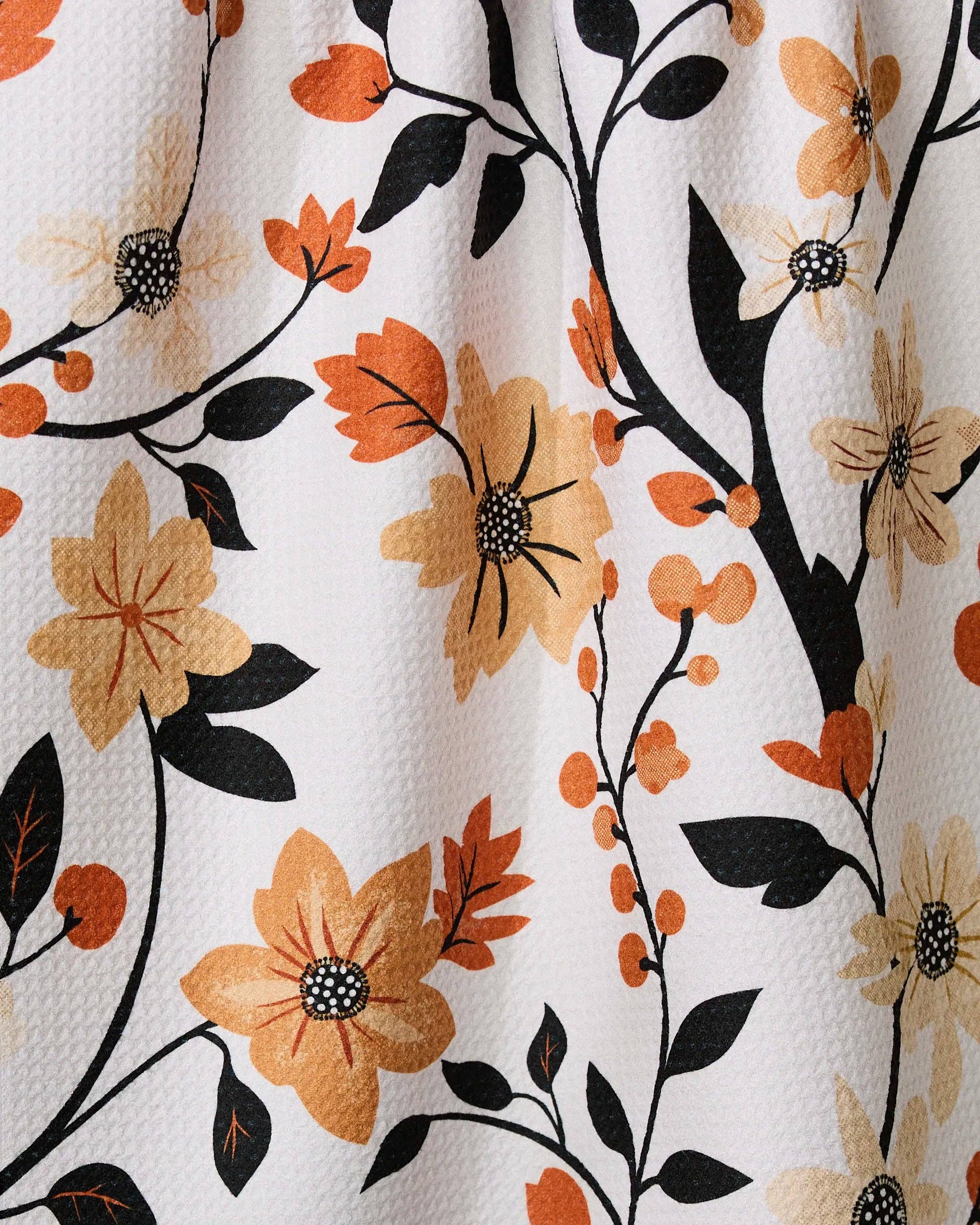 Close-up of floral pattern with orange, black, and beige flowers on a white background