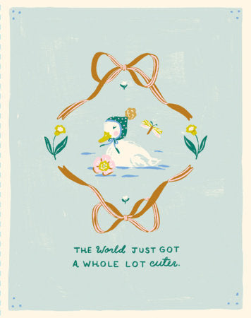 A square art print featuring a whimsical illustration of a white duck wearing a green bonnet in the center, framed by a large tan ribbon bow and small yellow flowers on a pale blue background. Below the illustration, the text reads, 'THE World JUST GOT A WHOLE LOT cuter.