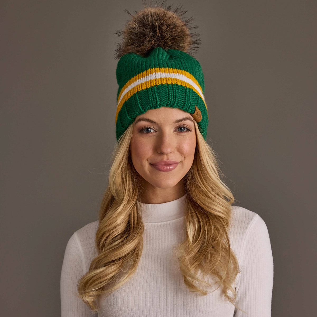 Panache Apparel Co. green, gold, and white striped knit pom hat with faux fur pom